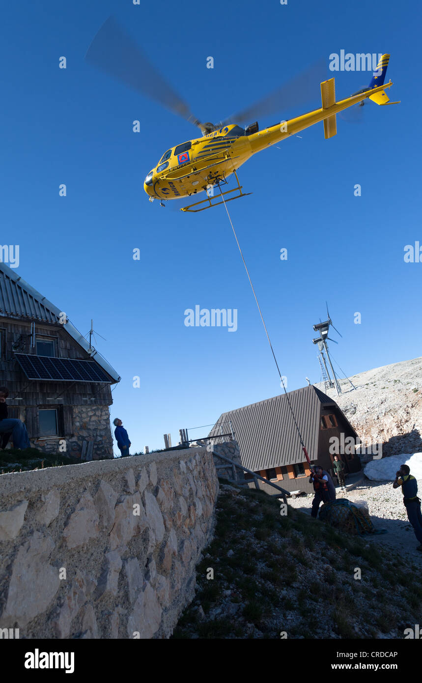 Ein Hubschrauber abfällt Nahrungs- und Wasservorräte zu Berghütte Triglavski Dom in den Julischen Alpen, Slowenien Stockfoto