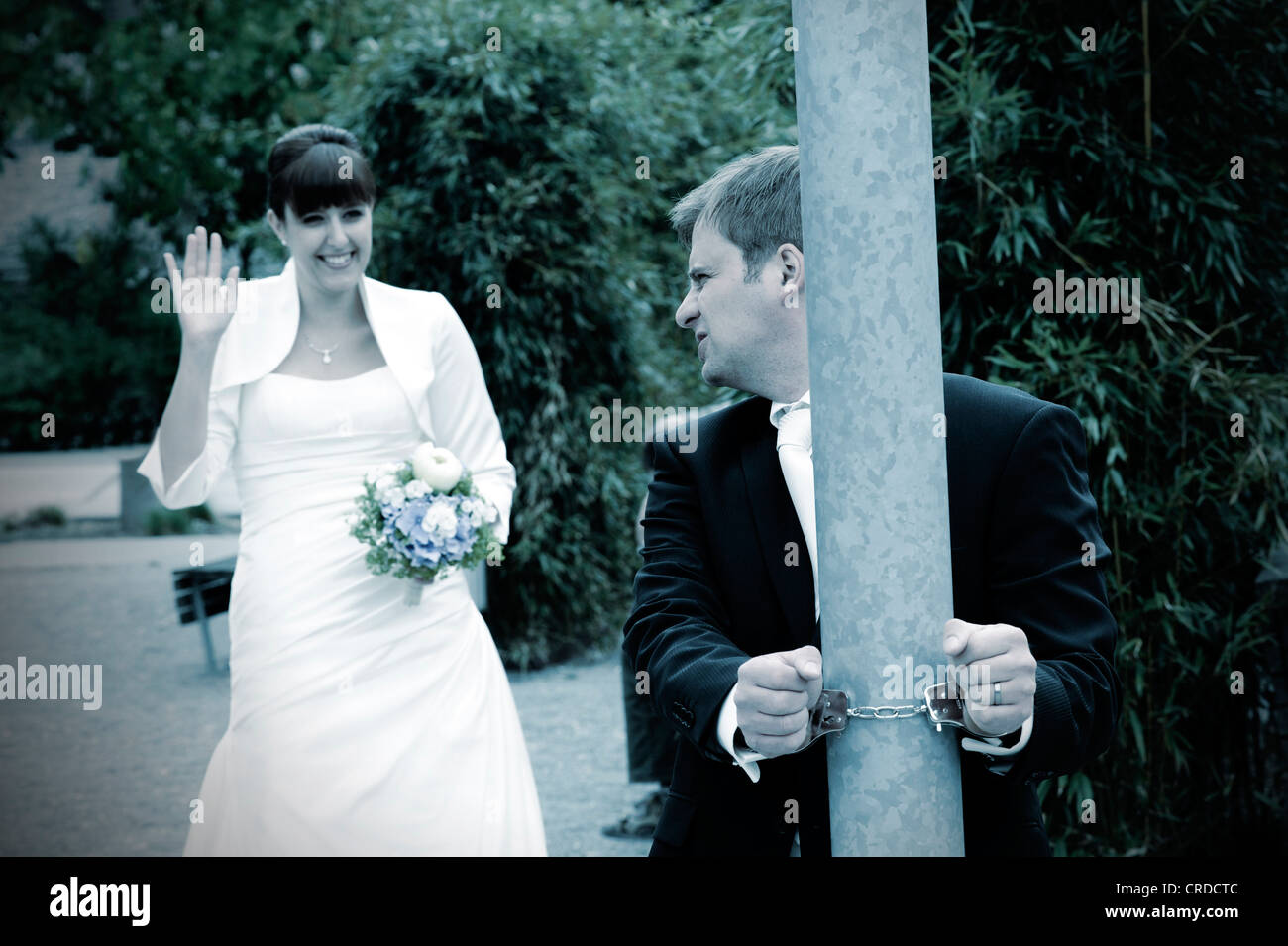 Bräutigam ist ein Pol der Braut Wellen und lächelt mit Handschellen gefesselt. Stockfoto