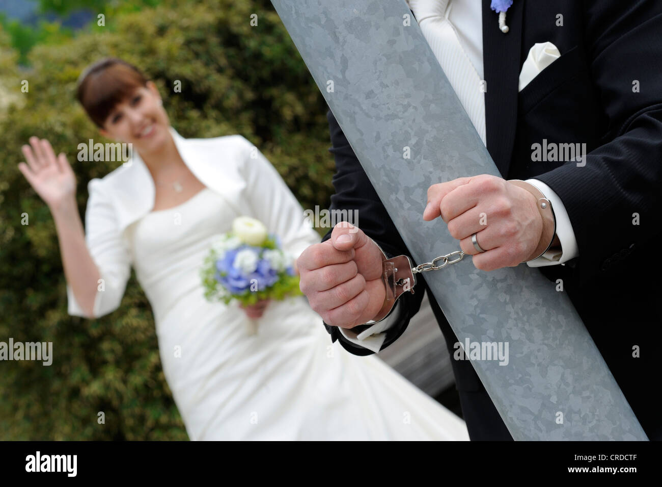 Bräutigam ist ein Pol während der Braut Wellen mit Handschellen gefesselt. Stockfoto