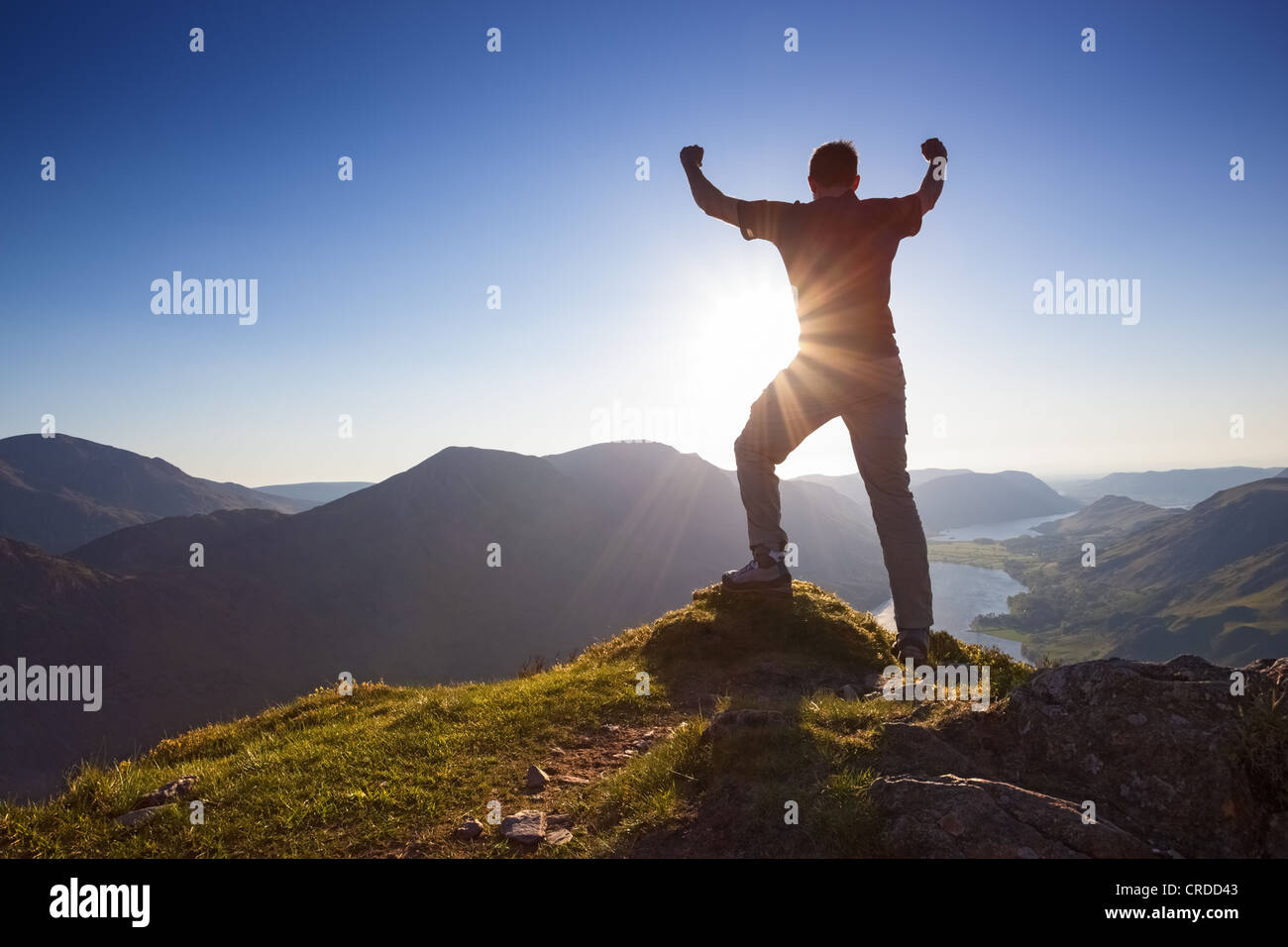 Man feiert mit seinen Armen gestreckt in der Luft auf dem Gipfel eines Berges. Stockfoto