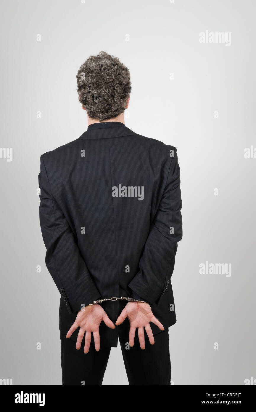 Geschäftsmann, tragen einen schwarzen Anzug, seine Hände hinter seinem Rücken mit Handschellen gefesselt Stockfoto