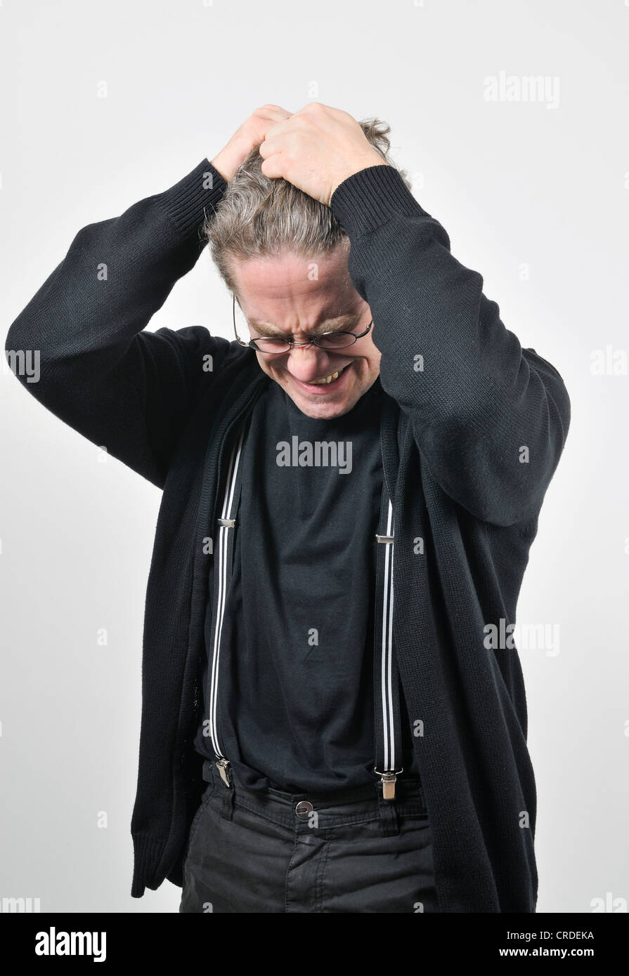 Junger Mann mit Brille, verzweifelt und wütend reißt seine Haare Stockfoto