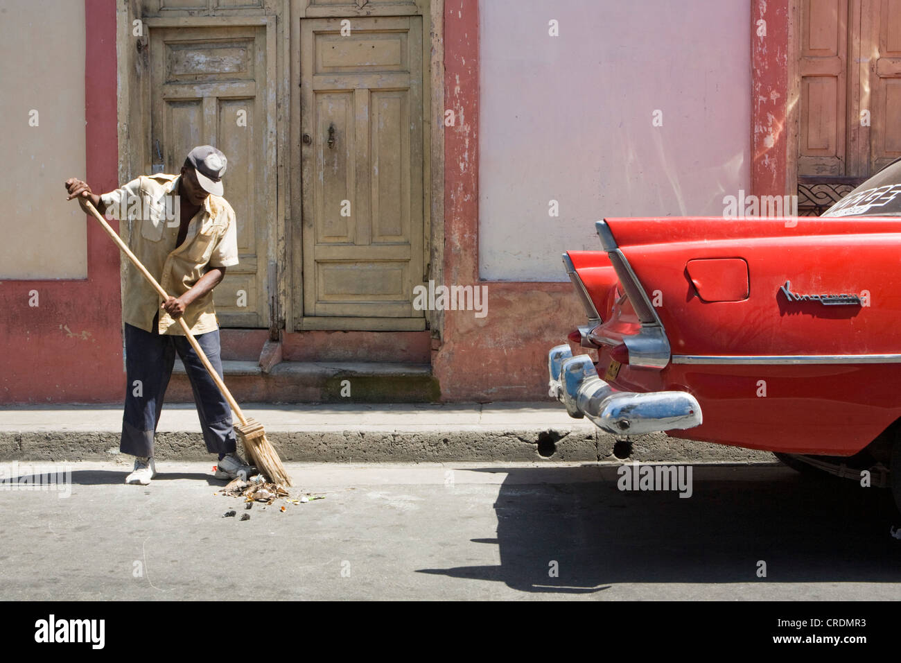 Kehrmaschine und klassische amerikanische Straßenauto in der Altstadt, Santiago De Cuba, Kuba Stockfoto
