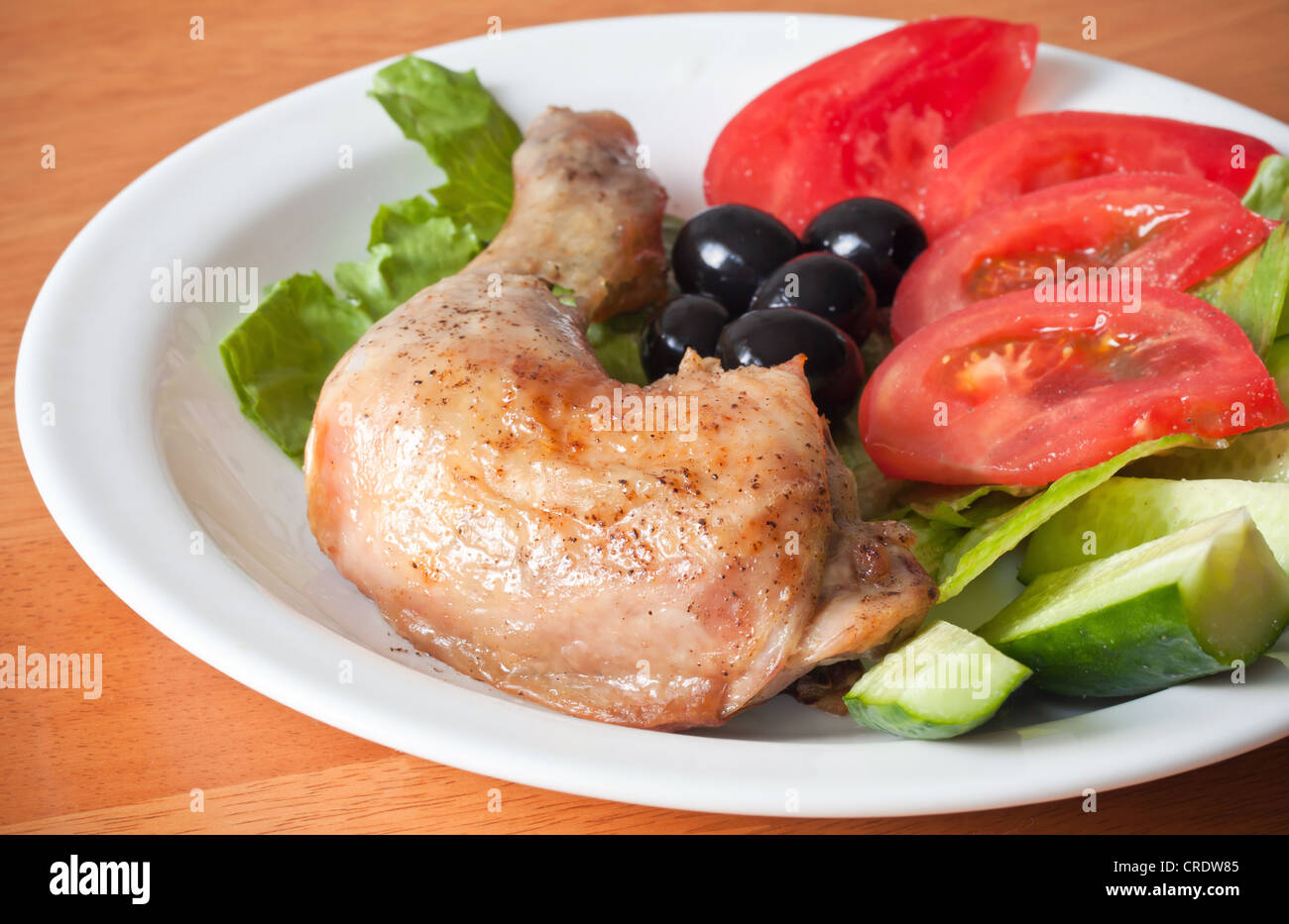 Gebratene Hühnerkeule mit Salat und frischem Gemüse Stockfoto