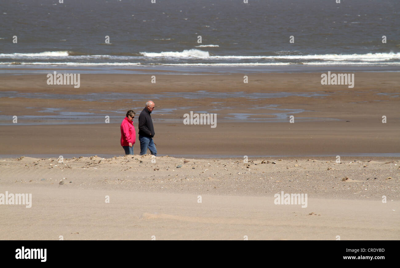 Paare, die auf einsamen windigen Strand. Stockfoto