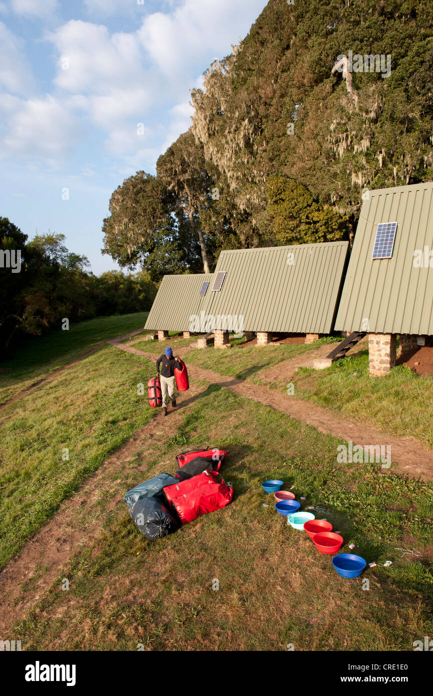 Bergsteigen, trekking, Gepäckträger mit Gepäck vor Berg Hütten, Kunststoff-Schalen für das Waschen, Mandara Hütte, Marangu-route Stockfoto
