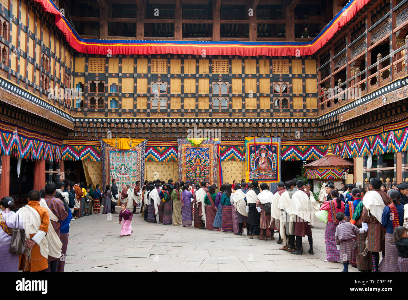 Tibetisch-buddhistische Festival Gewand Menschen tragen die traditionelle Gho stehen in einer Warteschlange, Rinpung Dzong Kloster und Festung Stockfoto