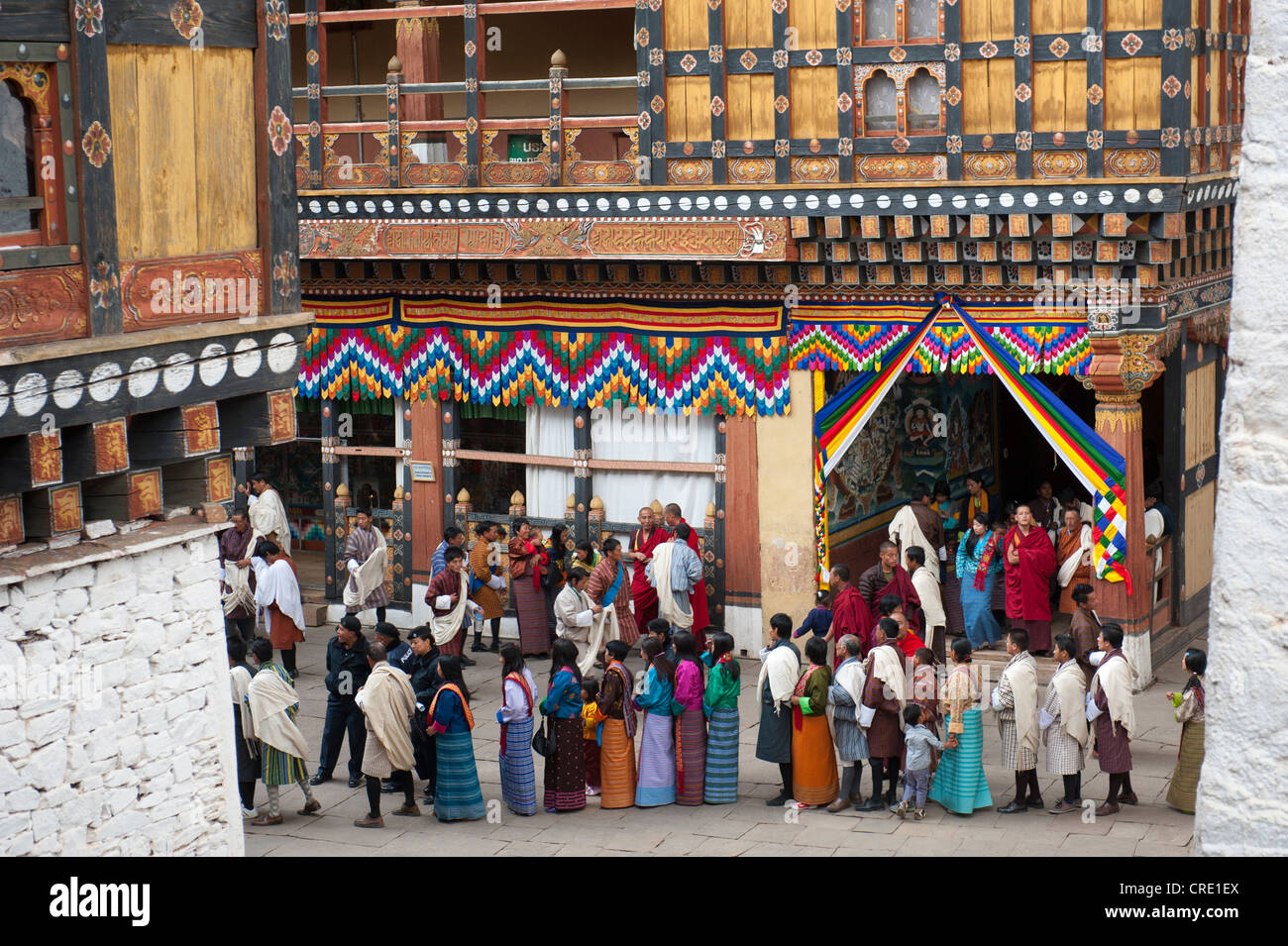 Tibetisch-buddhistische Festival Gewand Menschen tragen die traditionelle Gho stehen in einer Warteschlange, Rinpung Dzong Kloster und Festung Stockfoto