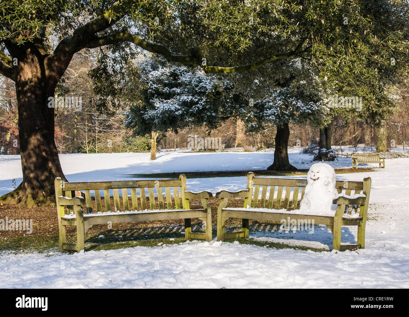 Schneemann sitzen auf einer Bank im Schnee bedeckt die Kew Gardens im Winter, Royal Botanic Gardens, London Stockfoto