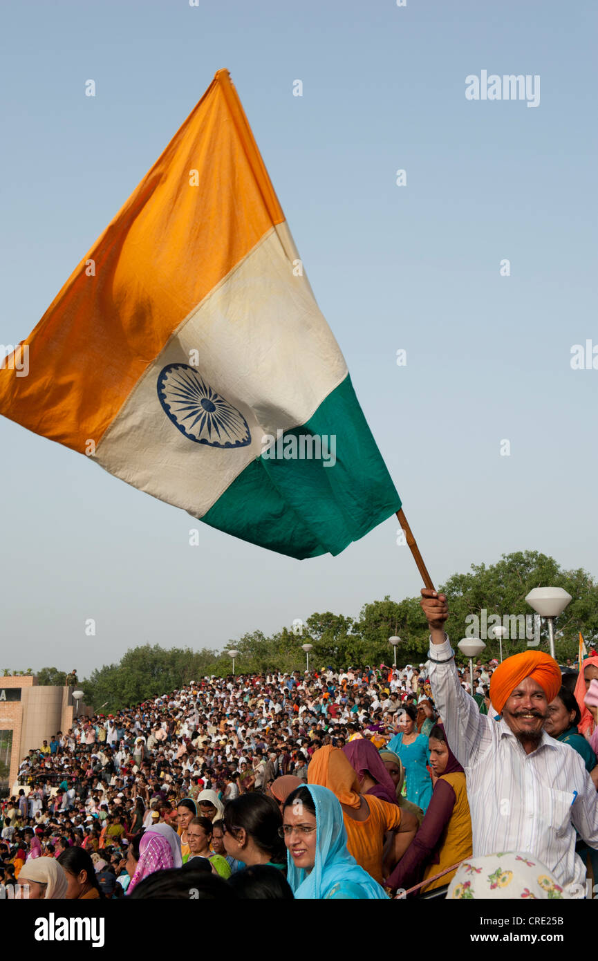 Mann mit Turban winken die indische Nationalflagge über eine Menschenmenge an der Grenze von Indien-Pakistan, Punjab, Indien Stockfoto