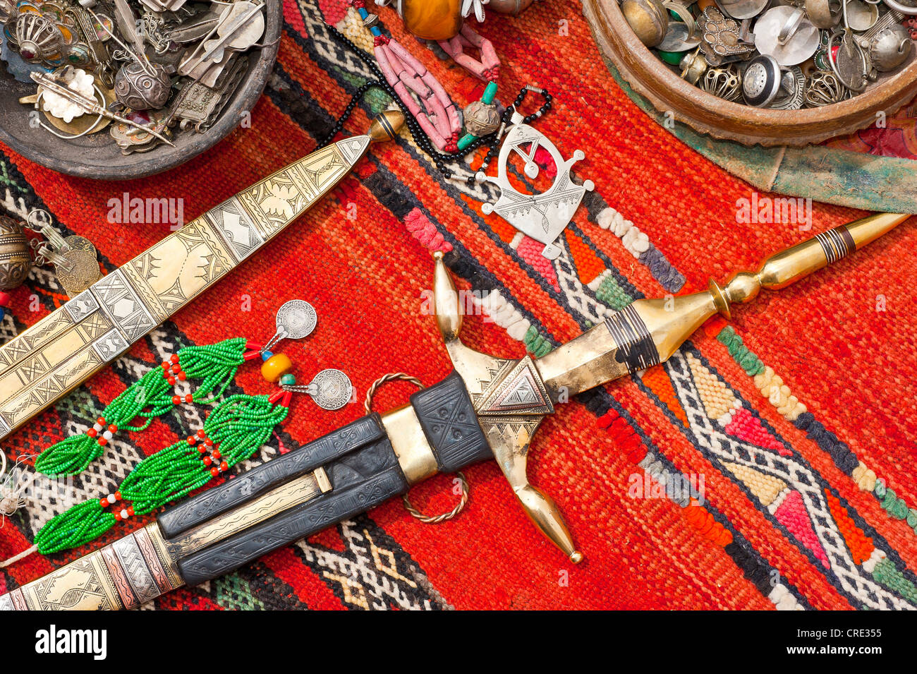Orientalischer Schmuck und reich verzierten Touareg Messer verteilen sich auf einem Teppich, Souk, Basar, Marokko, Afrika Stockfoto