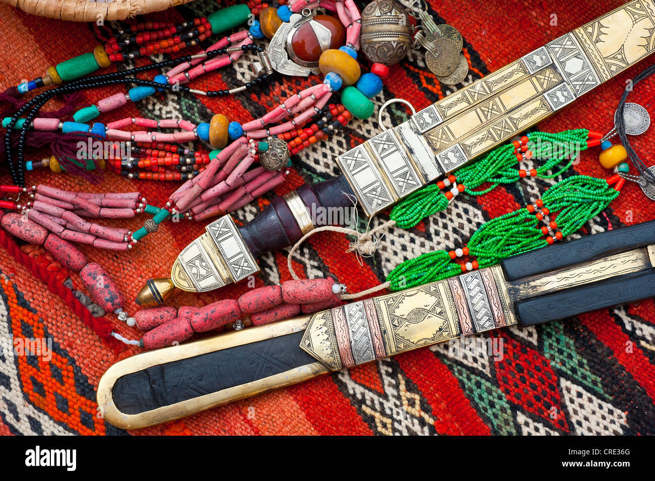 Orientalischer Schmuck und reich verzierten Touareg Messer verteilen sich auf einem Teppich in einem Souk oder Basar, Marokko, Afrika Stockfoto