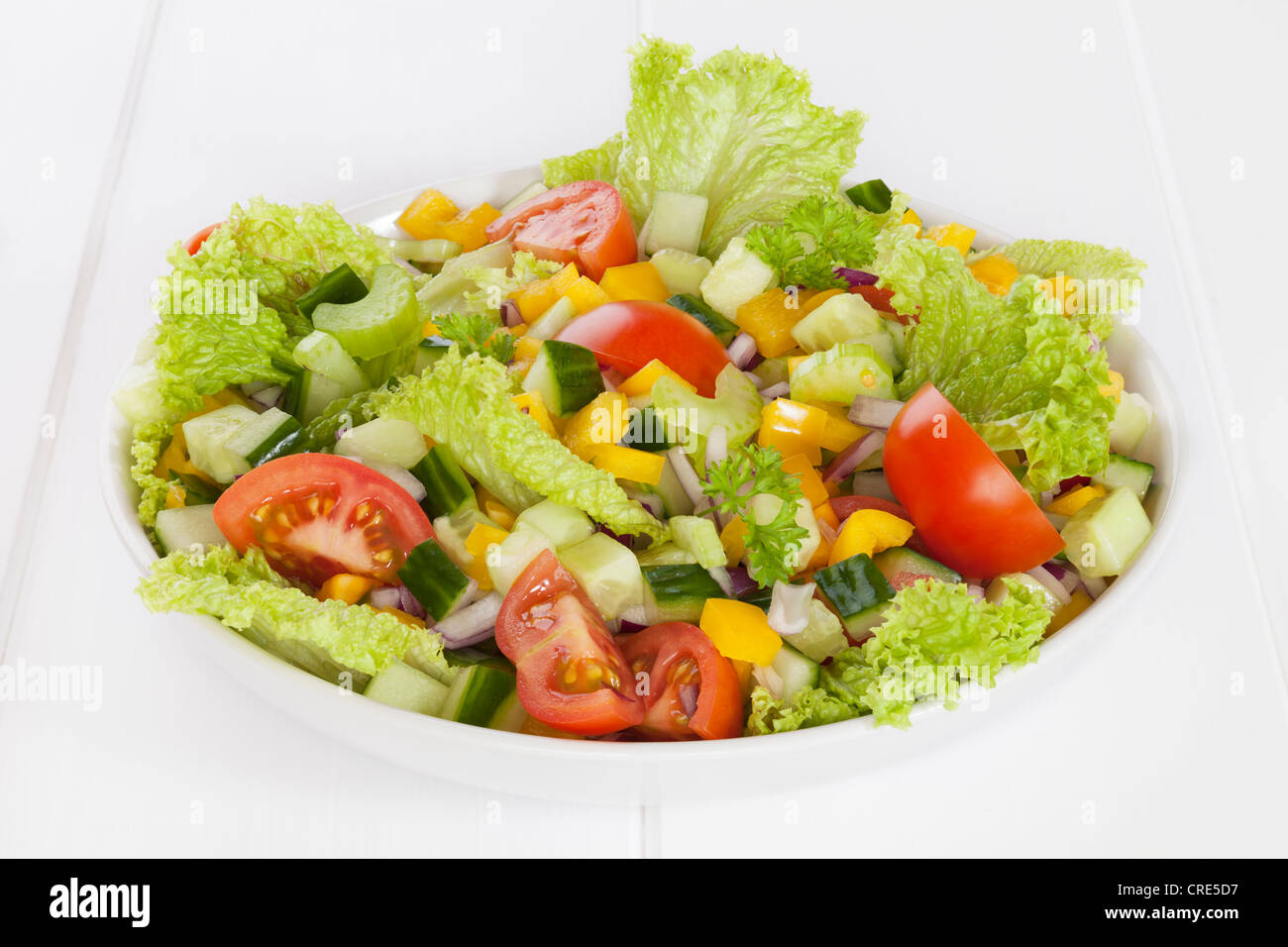 Eine Schale mit frischen gemischten Salat, Salat, Gurke, Tomate, rote Zwiebel, gelbe Paprika, Sellerie, Petersilie. Stockfoto