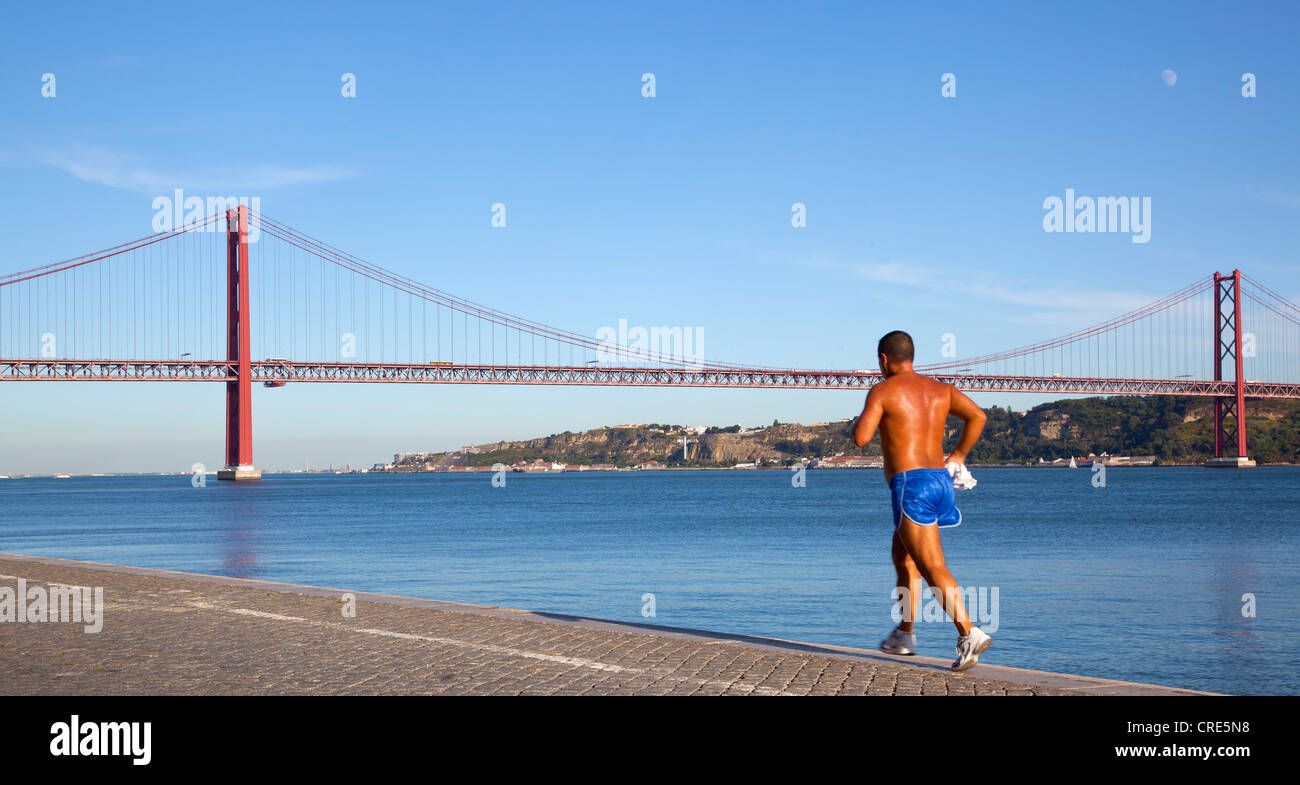 Jogger Joggen entlang am Ufer des Rio Tejo vor der Ponte tun 25 de Abril Brücke im Stadtteil Belem Stockfoto