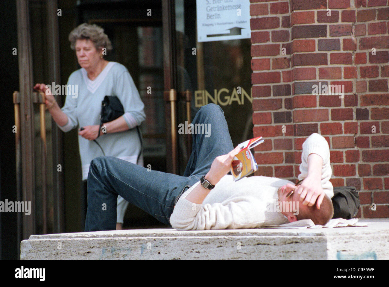Junger Mann liest auf einem konkreten Sockel, Berlin, Deutschland Stockfoto