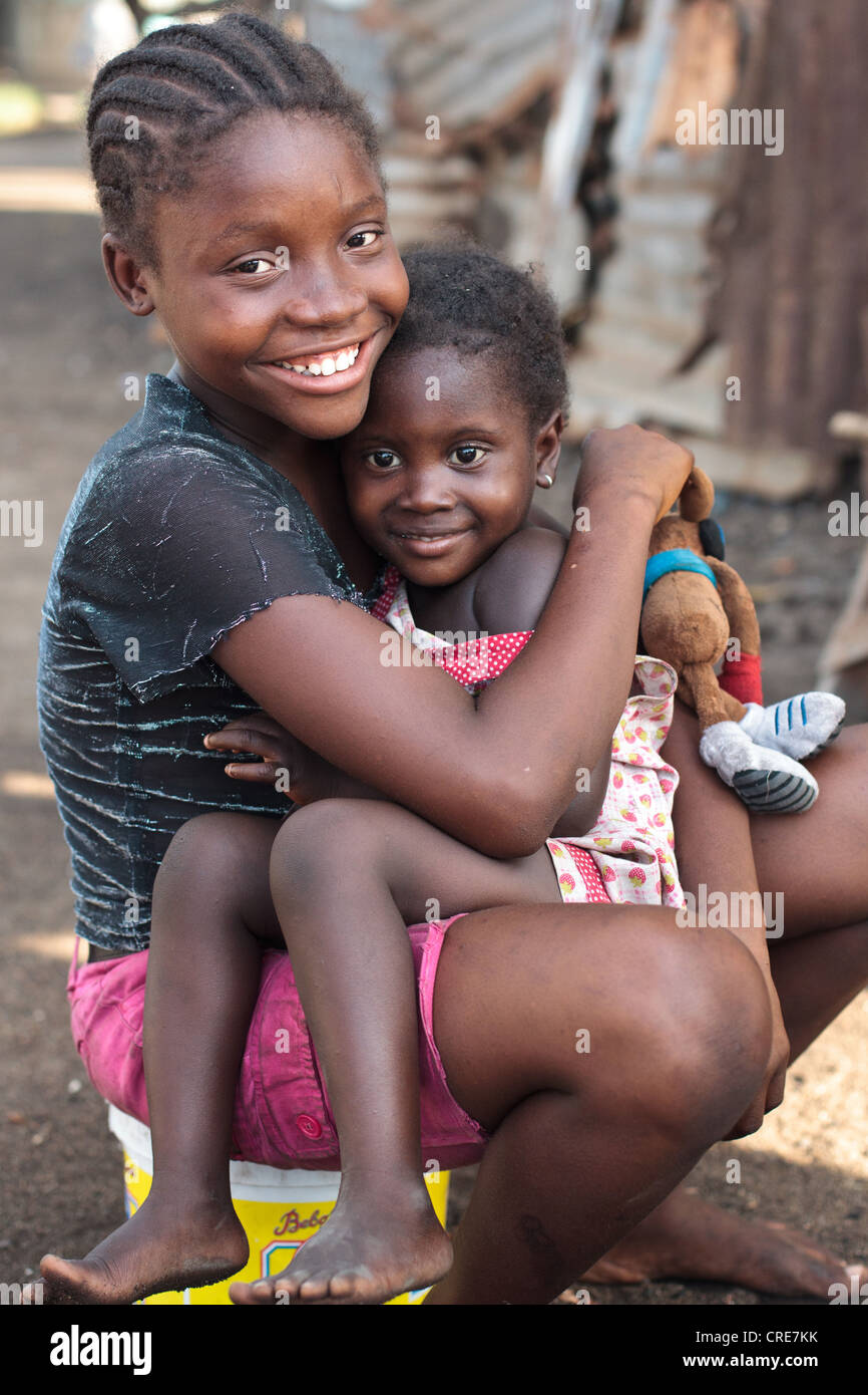 Eine Mädchen hält ein jüngeres Kind auf dem Schoß im Slum Clara Town in Monrovia, Liberia Montserrado county Stockfoto