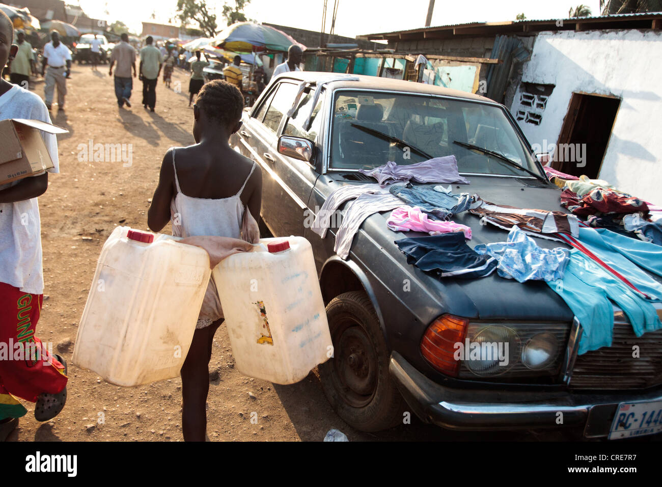 Eine Mädchen trägt zwei leere Kanister aus Kunststoff, wie sie leitet, um Wasser in die Clara Stadt Slum in Monrovia, Montserrado County kaufen Stockfoto