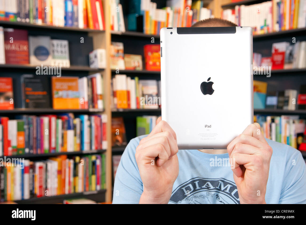 Mann hält ein iPad, e-Book oder e-Book-Reader vor seinem Gesicht in einer Buchhandlung in Regensburg, Bayern Stockfoto
