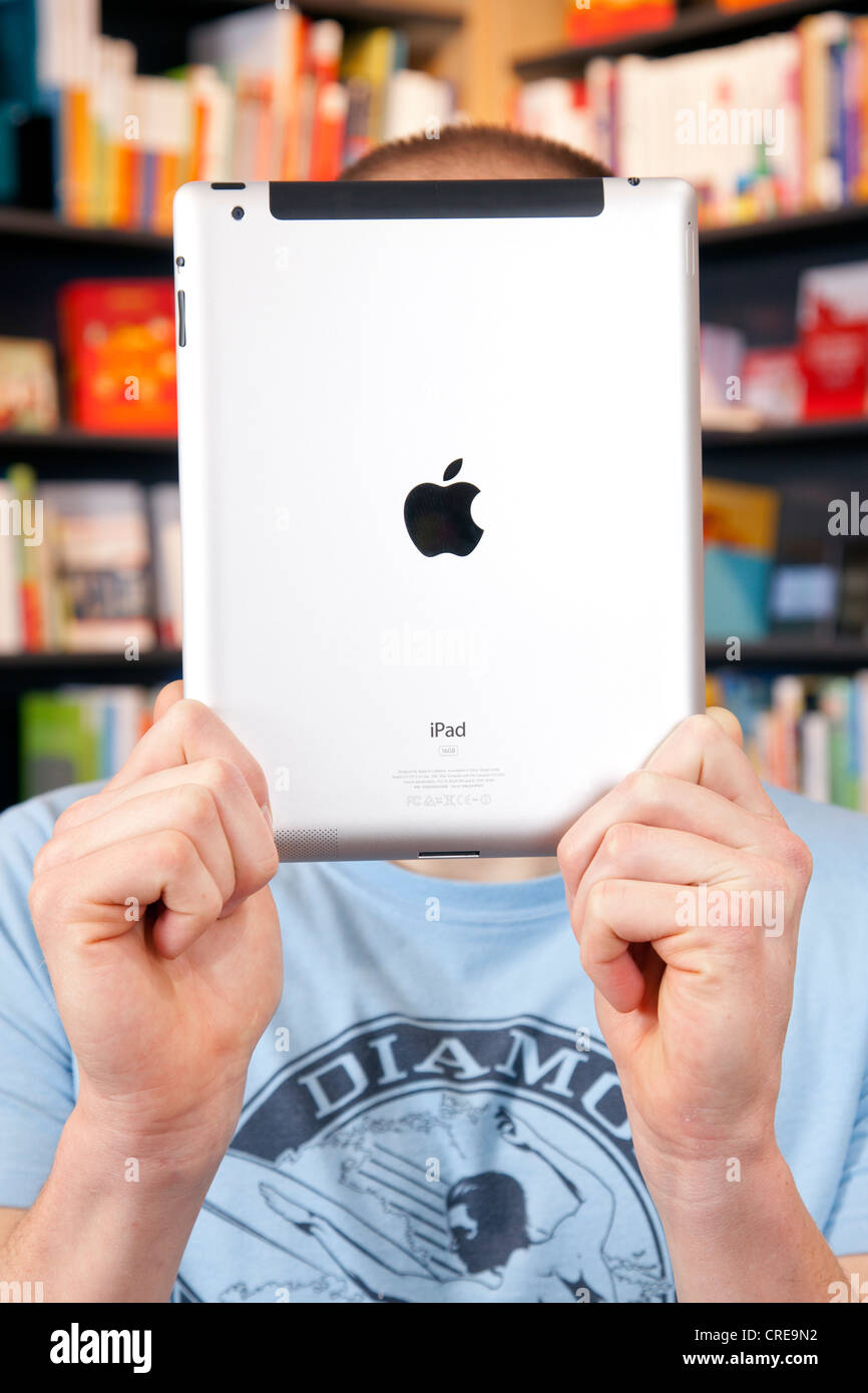 Mann hält ein iPad, e-Book oder e-Book-Reader vor seinem Gesicht in einer Buchhandlung in Regensburg, Bayern Stockfoto