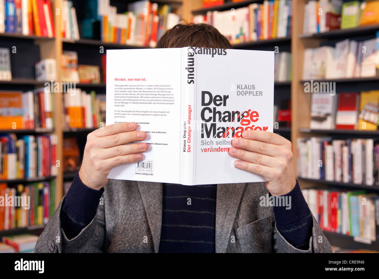 Mann, der vor seinem Gesicht, ein Buch in einer Buchhandlung in Regensburg, Bayern, Deutschland, Europa Stockfoto