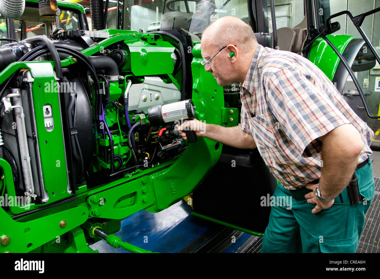 Endkontrolle, Mann auf der Suche nach einem Leck mit einer UV-Lampe im Bereich Traktor-Produktion in der Europazentrale von der Stockfoto