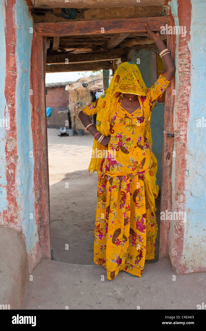 Junge verschleierte Inderin in einen Sari schauen neugierig aus ihren Eingang, Bishnoi, Jodhpur, Rajasthan, Indien, Asien Stockfoto