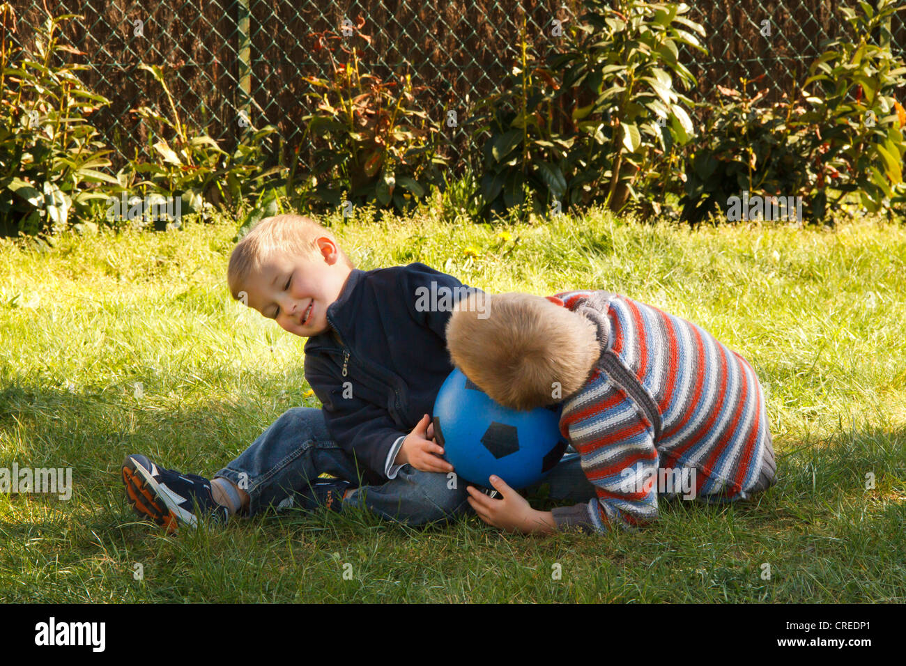 Brüder auf dem Rasen mit Fußball spielen. Stockfoto