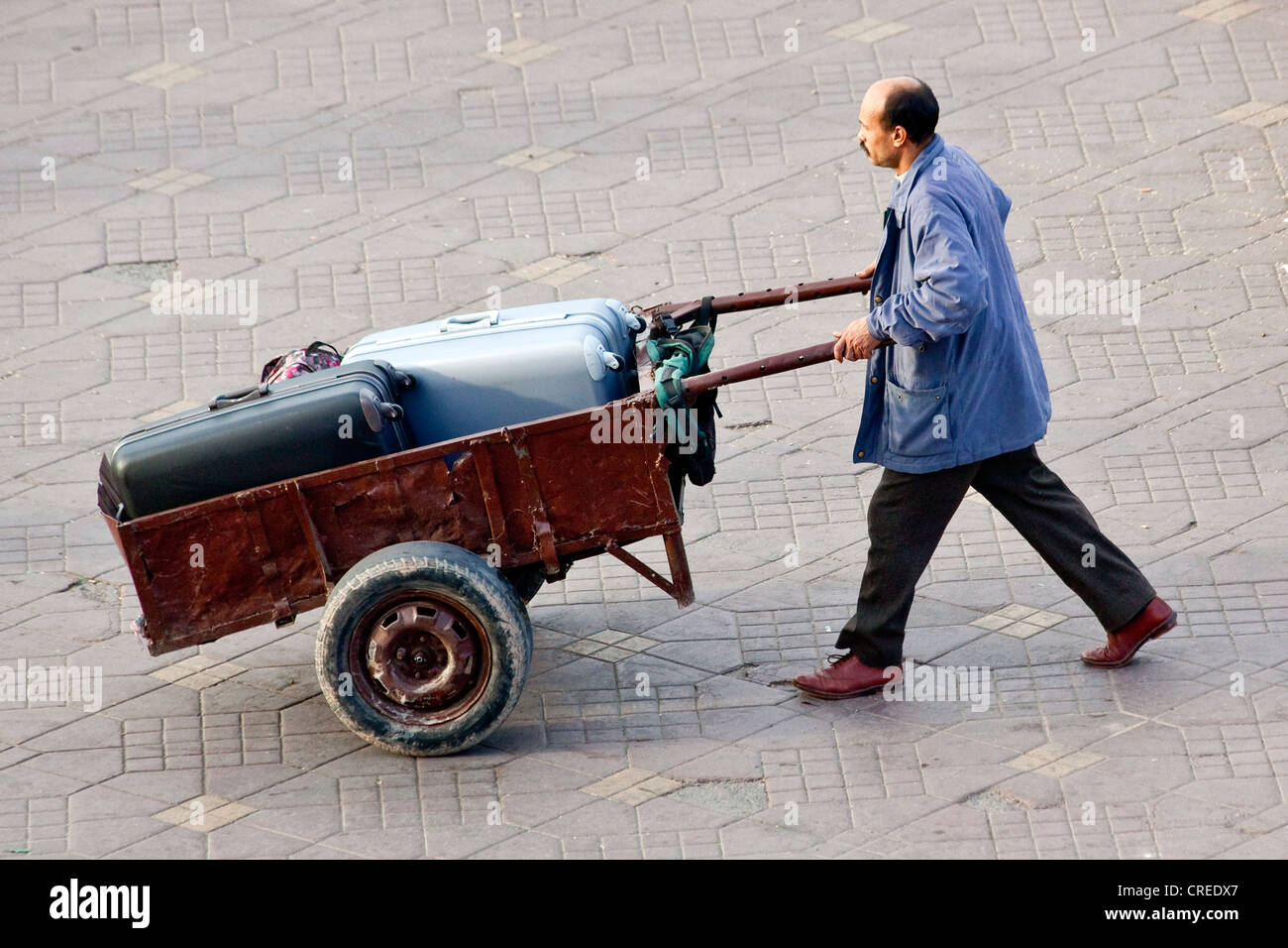 Mann Transport Koffer mit einem Handwagen in Platz Djemaa el Fna, Medina oder Altstadt, UNESCO-Weltkulturerbe, Marrakesch Stockfoto