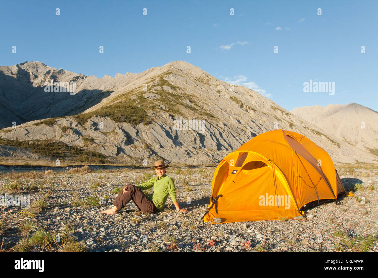 Junge Frau sitzen, entspannen, genießen das Abendlicht, Expedition Zelt, arktische Tundra, camping, Mackenzie Mountains hinter Stockfoto