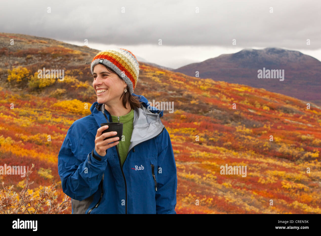 Junge Frau, Wanderer ruht, hält eine Tasse, subalpine Tundra, Indian Summer, Herbst, in der Nähe von Fish Lake, Yukon Territorium, Kanada Stockfoto