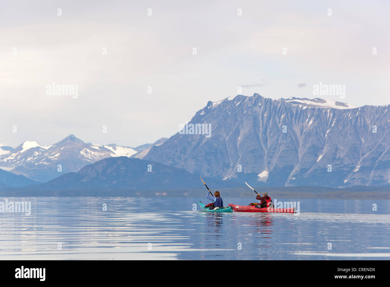 Zwei Frauen in See-Kajaks, Paddeln, Kajakfahren, Bergen im Hintergrund, Tagish Highland, Mount Fetterly, Atlin See, Britisch-Kolumbien Stockfoto