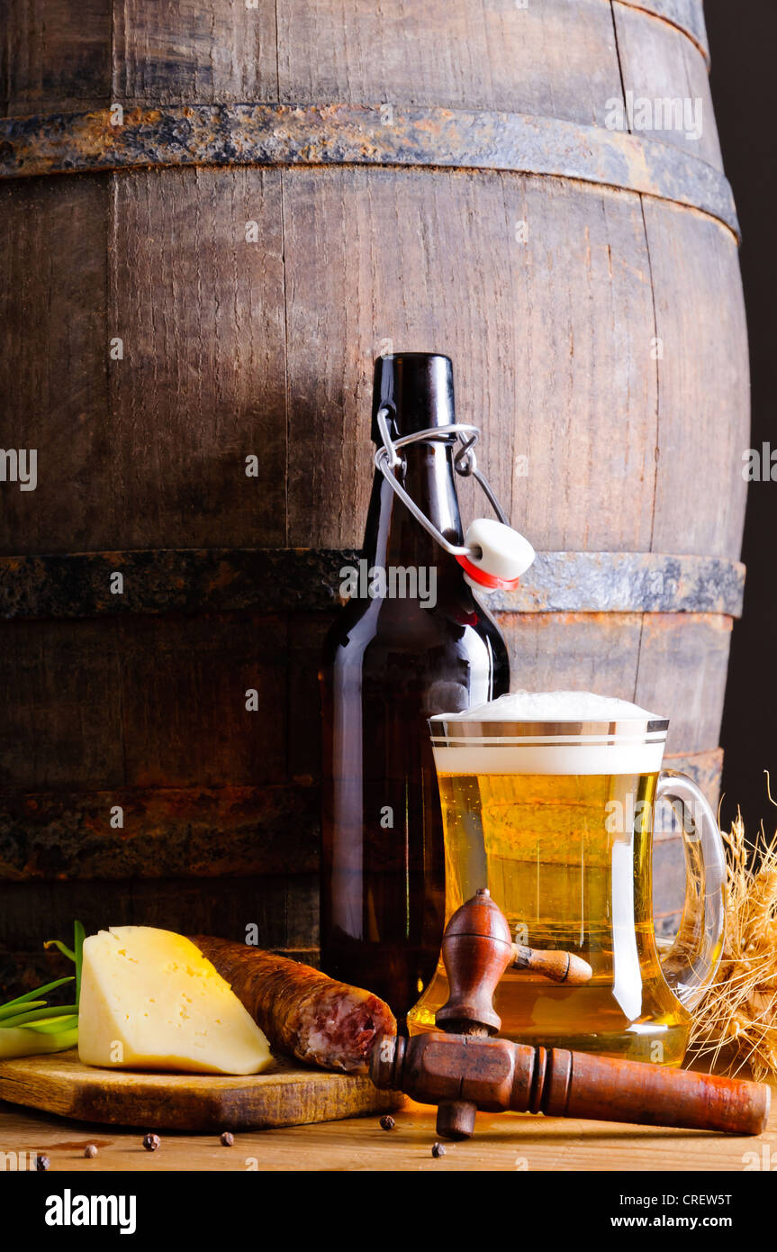 Stillleben mit hölzernen Bierfaß, Becher, Flasche und Essen Stockfoto