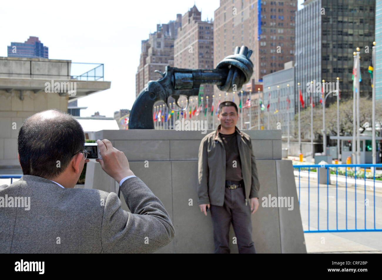 Touristen die Souvenir-Fotos vor der verknoteten Gewehr, Gewaltlosigkeit Skulptur aus Reuterswaerd vor UN-Hauptquartier, USA, USA, New York City, Manhattan Stockfoto