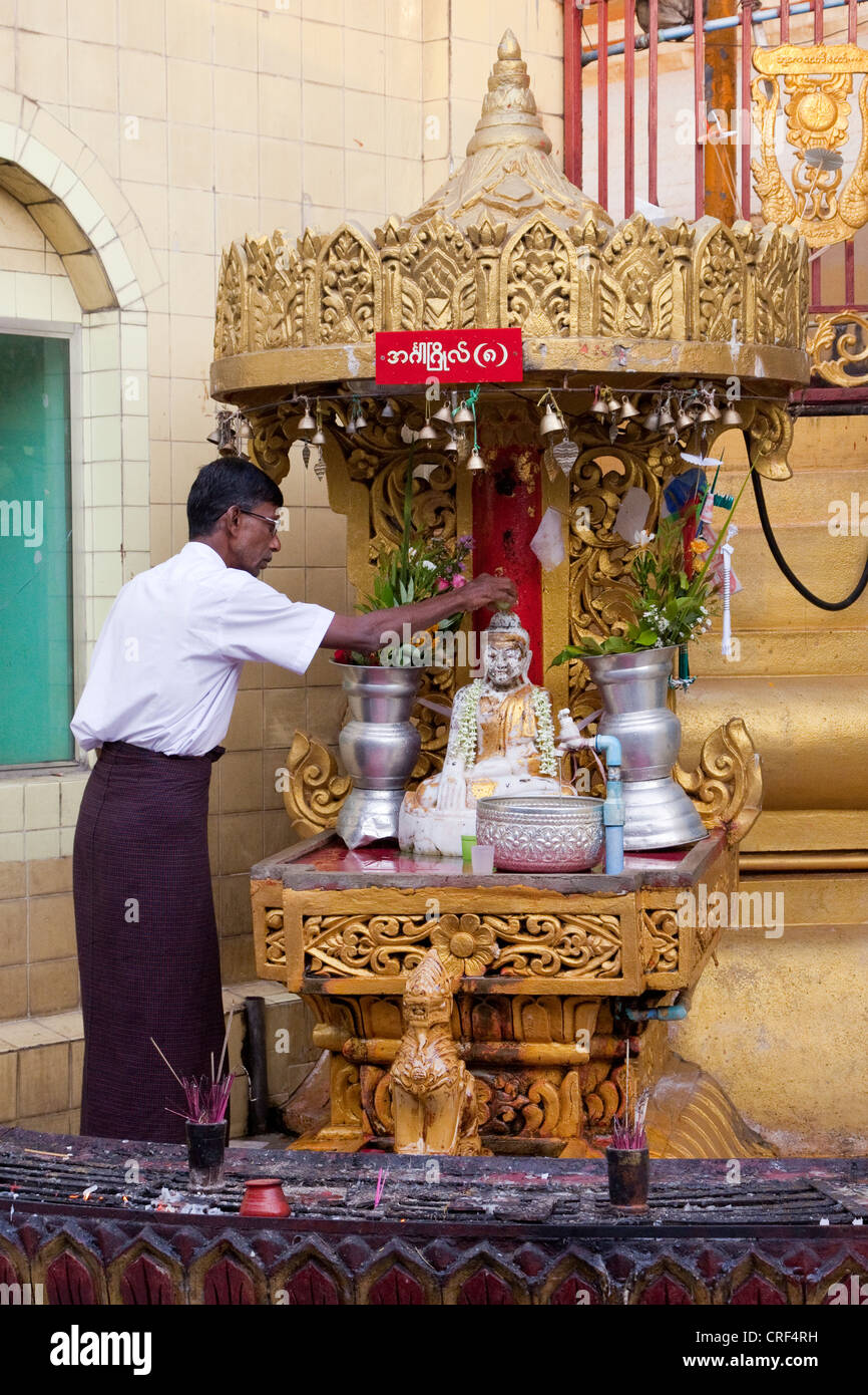 Myanmar, Burma, Yangon. Sule-Pagode. Verehrer gießen Wasser über kleine Buddha-Statue. Stockfoto