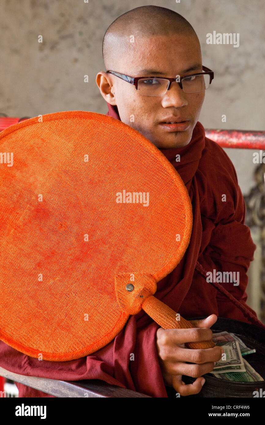 Myanmar, Burma, Yangon. Sule-Pagode. Young buddhistischer Mönch mit einem Ventilator, US-Dollar in seine Schale betteln. Stockfoto