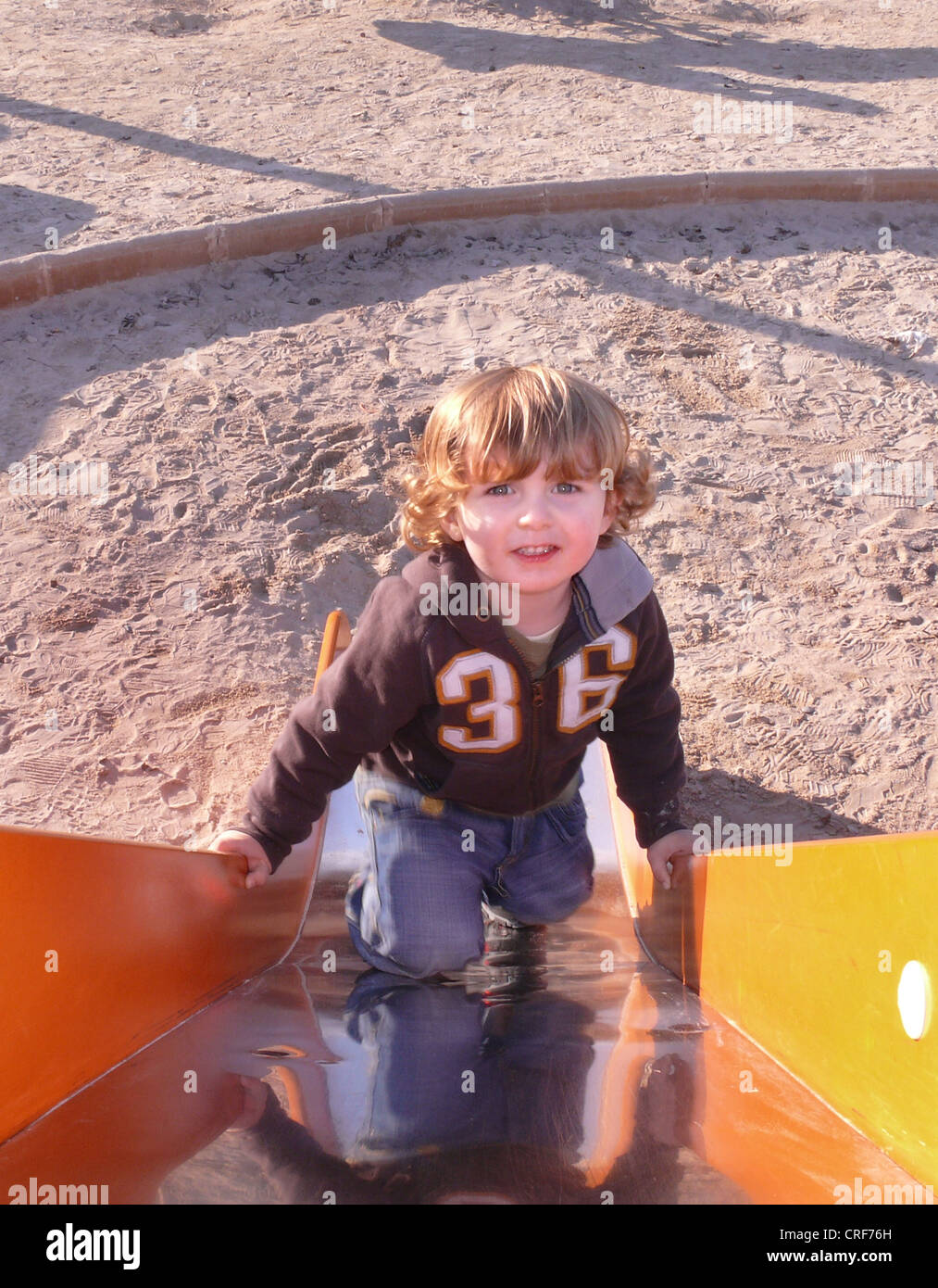 kleiner Junge Klettern eine Scheibe auf einem Spielplatz Stockfoto