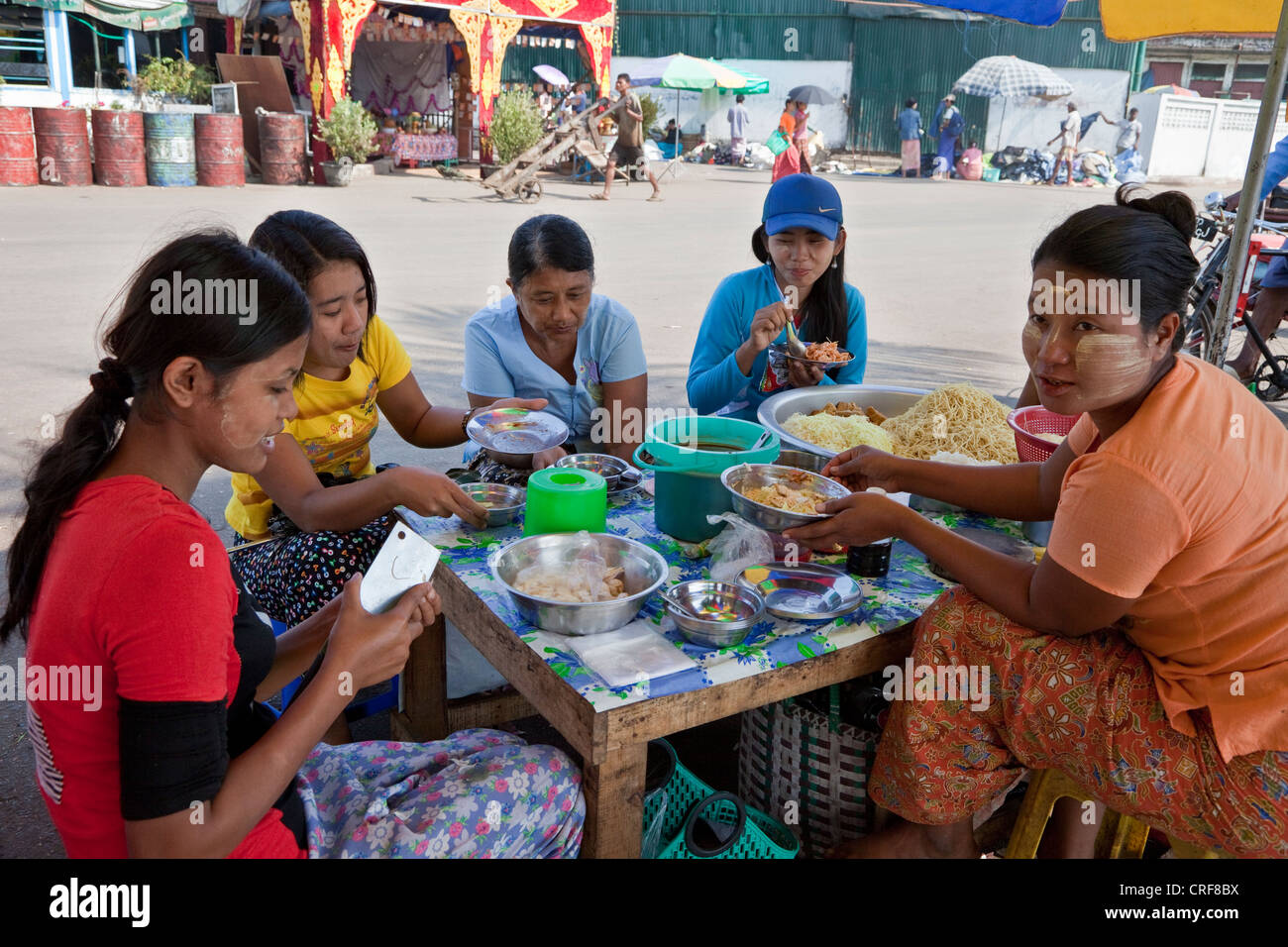 Myanmar, Burma, Yangon. Kunden zu Mittag am Stand des Anbieters Street Food. Stockfoto