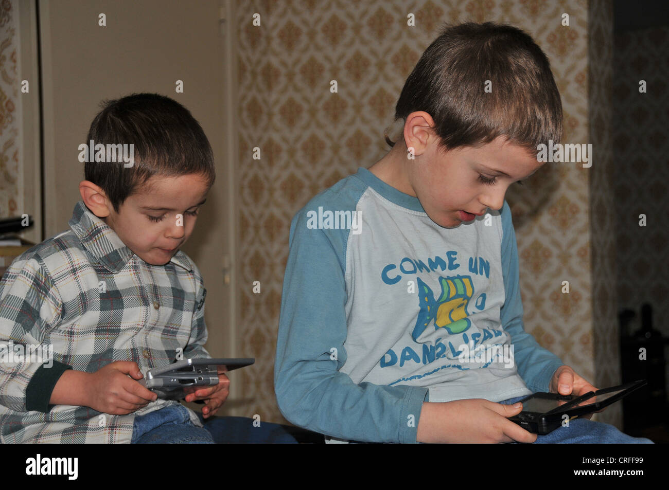 Kinder spielen elektronische Spiel im Apartment, Frankreich Stockfoto