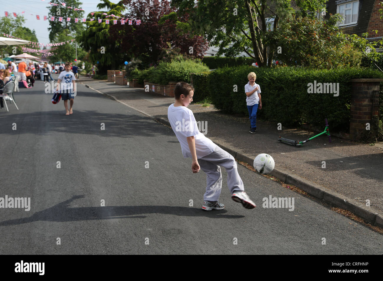Jungs spielen Fußball am Straßenfest feiert die Königin Diamond Jubilee Surrey England Stockfoto