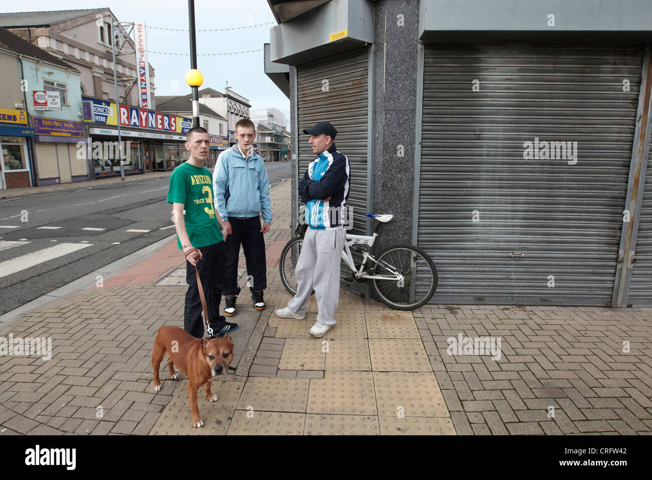 Grimsby Straßenszene - junge Männer an Straßenecke mit Hund, Freeman Street, Grimsby, Lincolnshire, England, UK Stockfoto