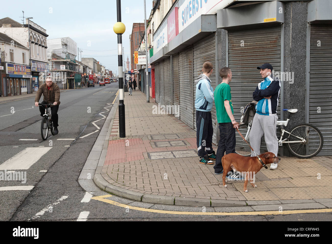 Grimsby Straßenszene - junge Männer an Straßenecke mit Hund, Freeman Street, Grimsby, Lincolnshire, England, UK Stockfoto