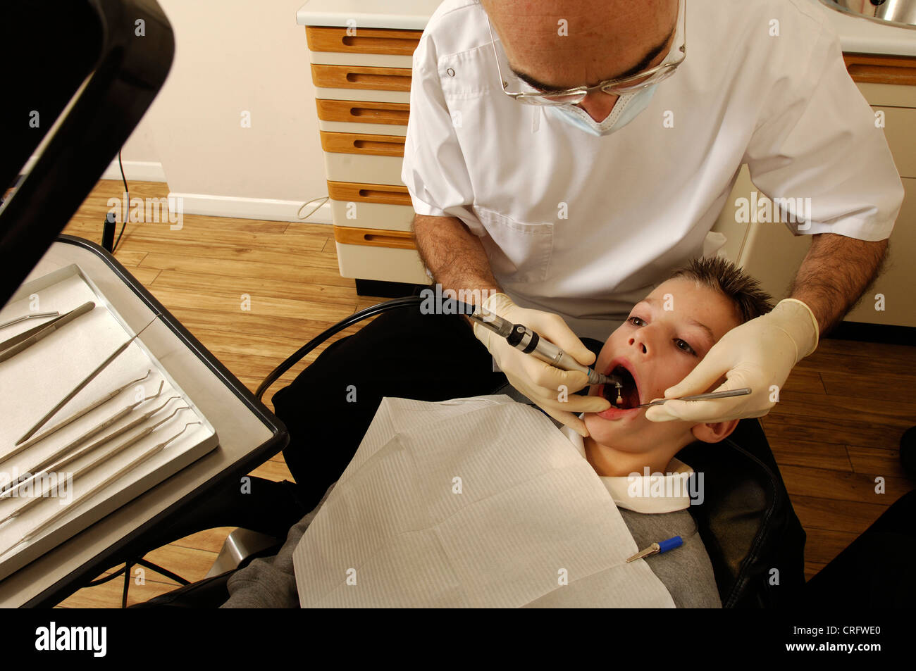 Ein Zahnarzt mit einer elektronischen Pinsel um zu Plaque aus ein kleiner Junge Zähne zu entfernen. Stockfoto
