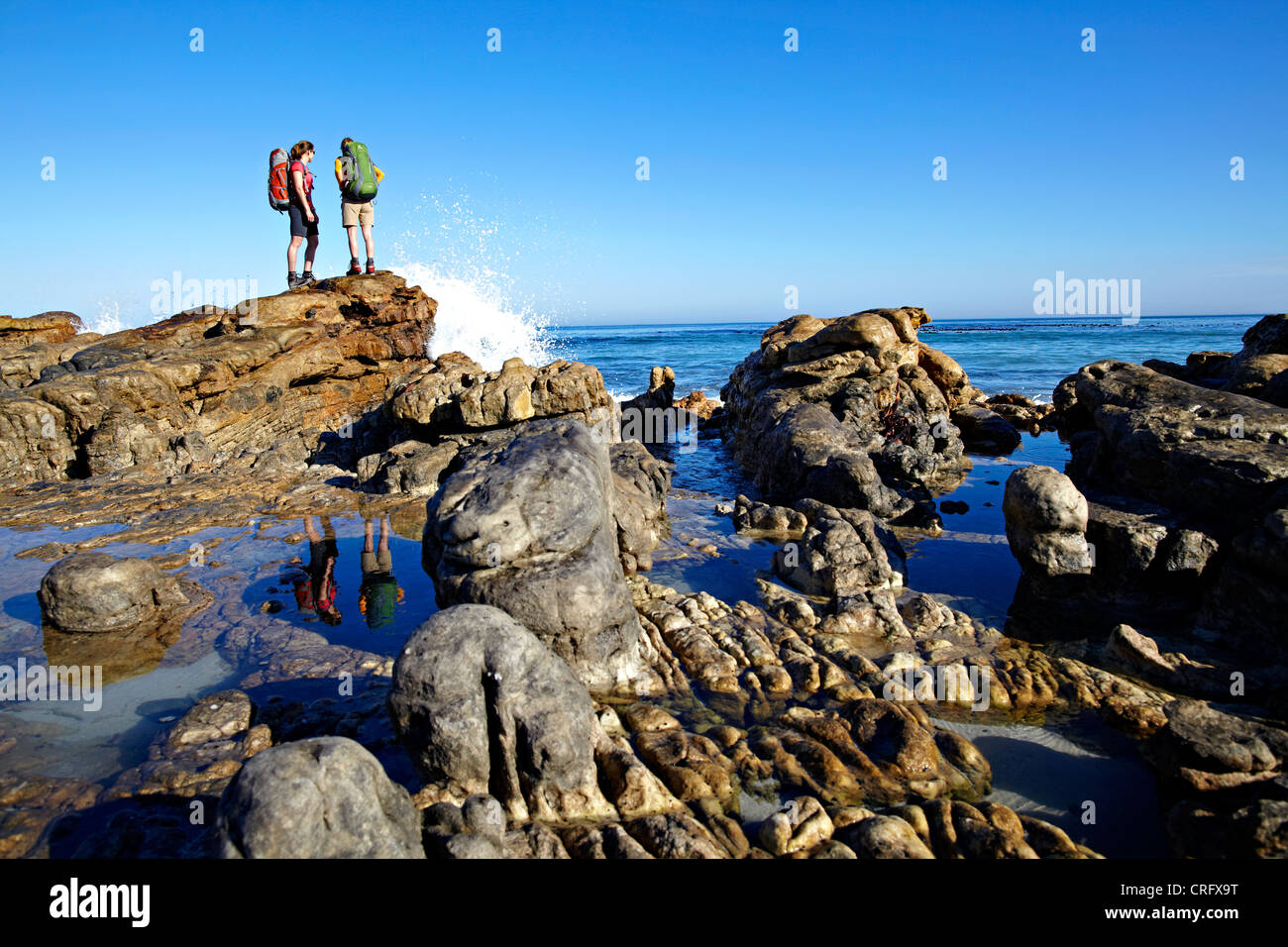 Zwei Frauen stehen auf einigen Felsen an Noordhoek Strand in der Nähe von Kapstadt. Südafrika. Stockfoto