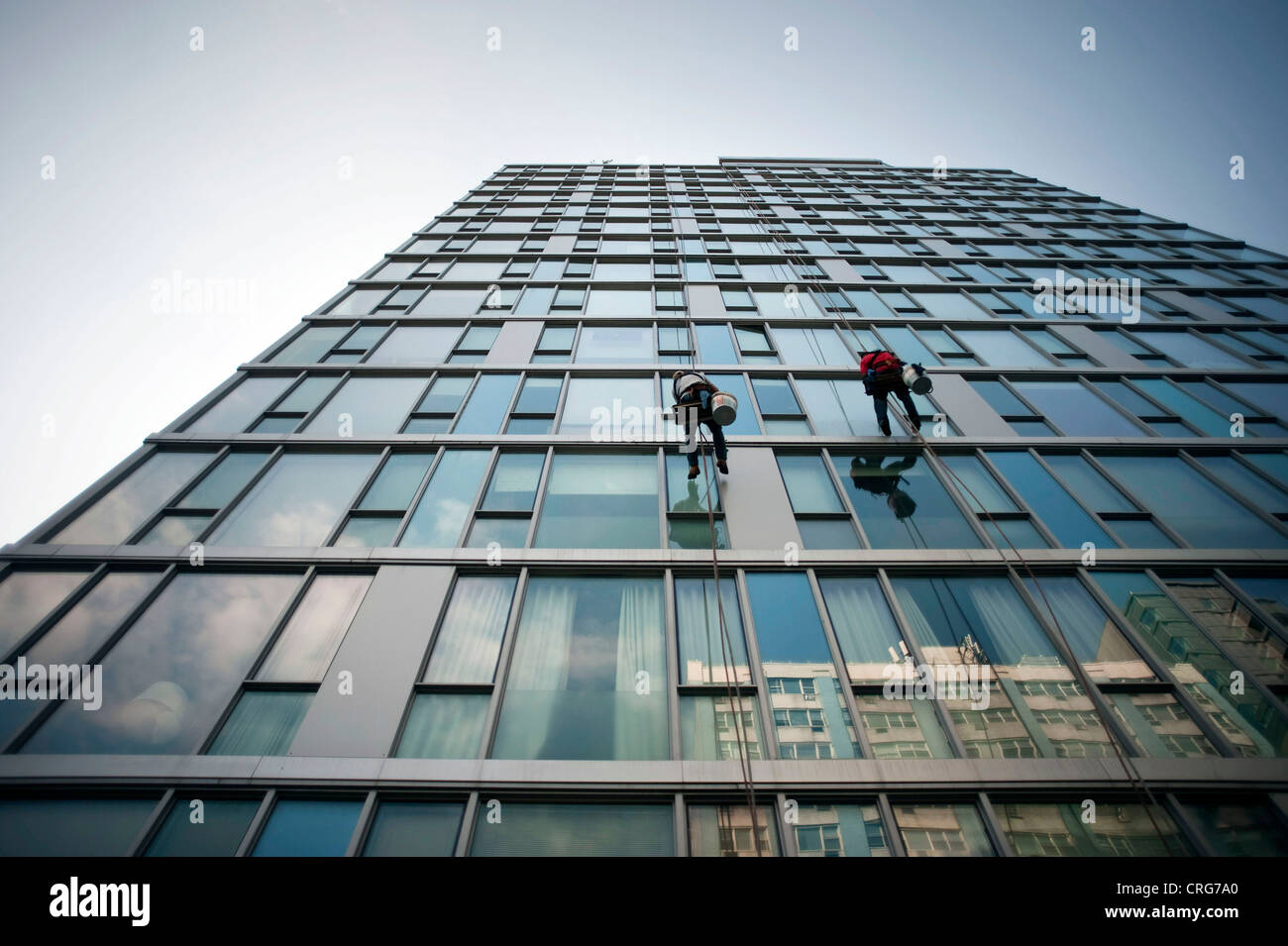 Fenster Scheiben arbeiten, baumelte ein Glas-seitig Gebäude hoch über Dritte Allee in East Village in Manhattan. Stockfoto
