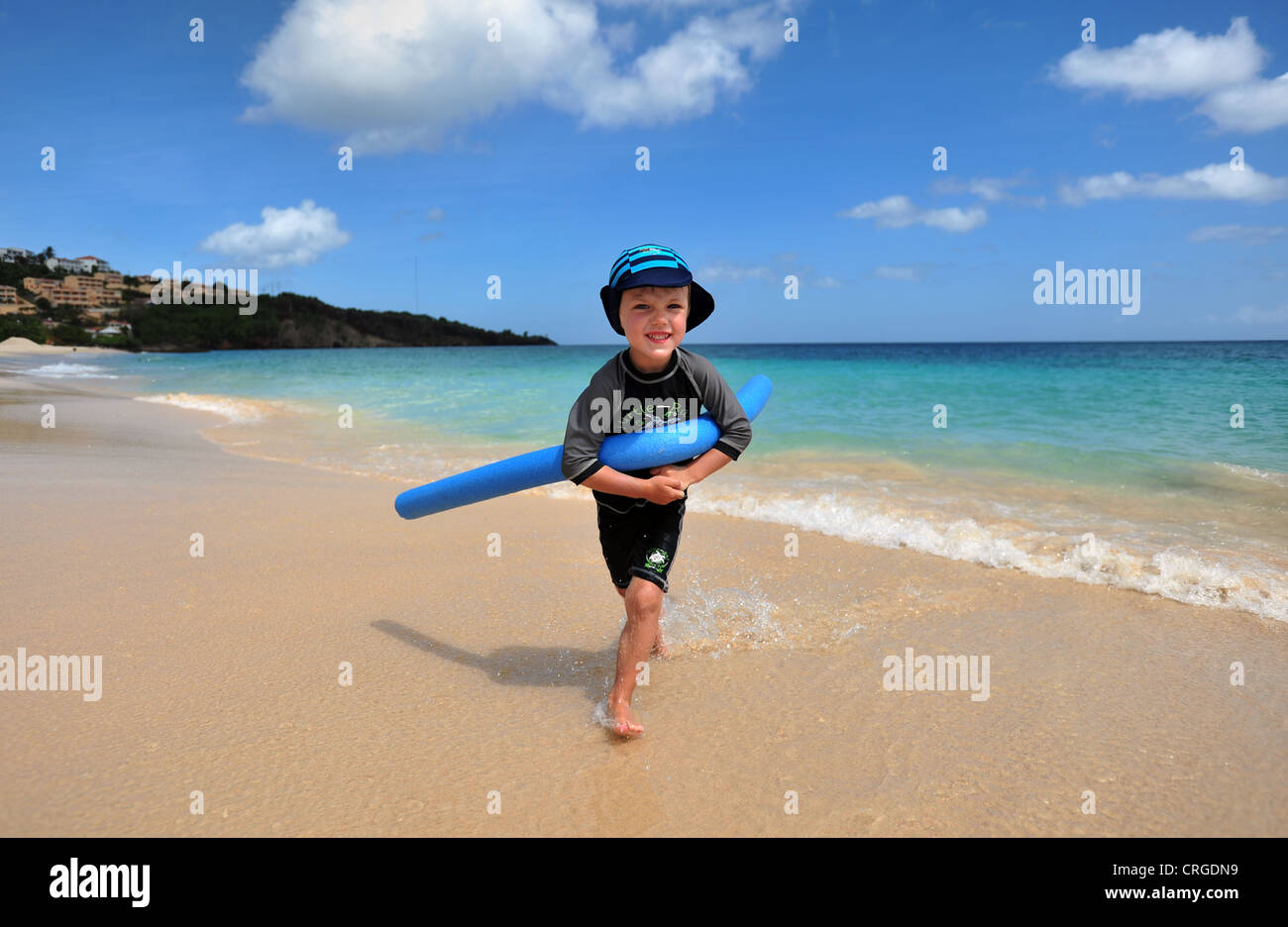 Ein vier Jahre alter Junge mit einer Schwimmhilfe am Strand spielt beach Grand Anse, Grenada, Karibik, West Indies Stockfoto