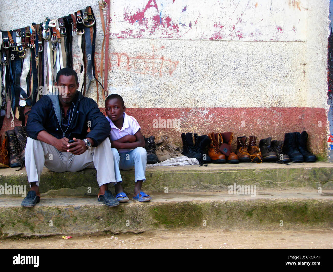 Mann und junge Junge sitzt vor Schuhe und Gürtel für Verkauf, Haiti, Provinz de l ' Ouest, Kenskoff, Port-Au-Prince Stockfoto