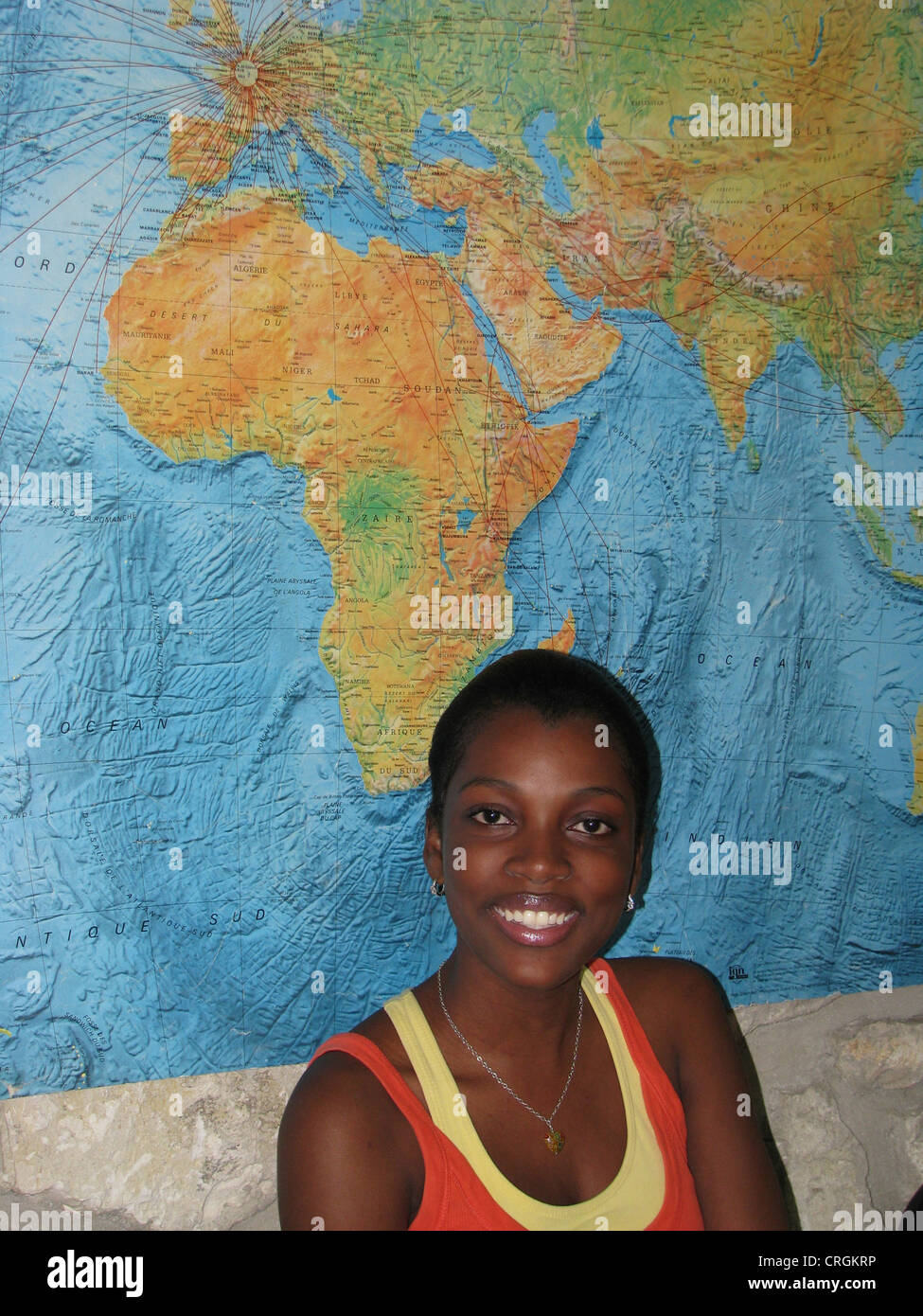 Junge schwarze Frau sitzt vor afrikanischen Kontinent auf der Weltkarte, Haiti, Provinz de l ' Ouest, Petionville, Port-Au-Prince Stockfoto