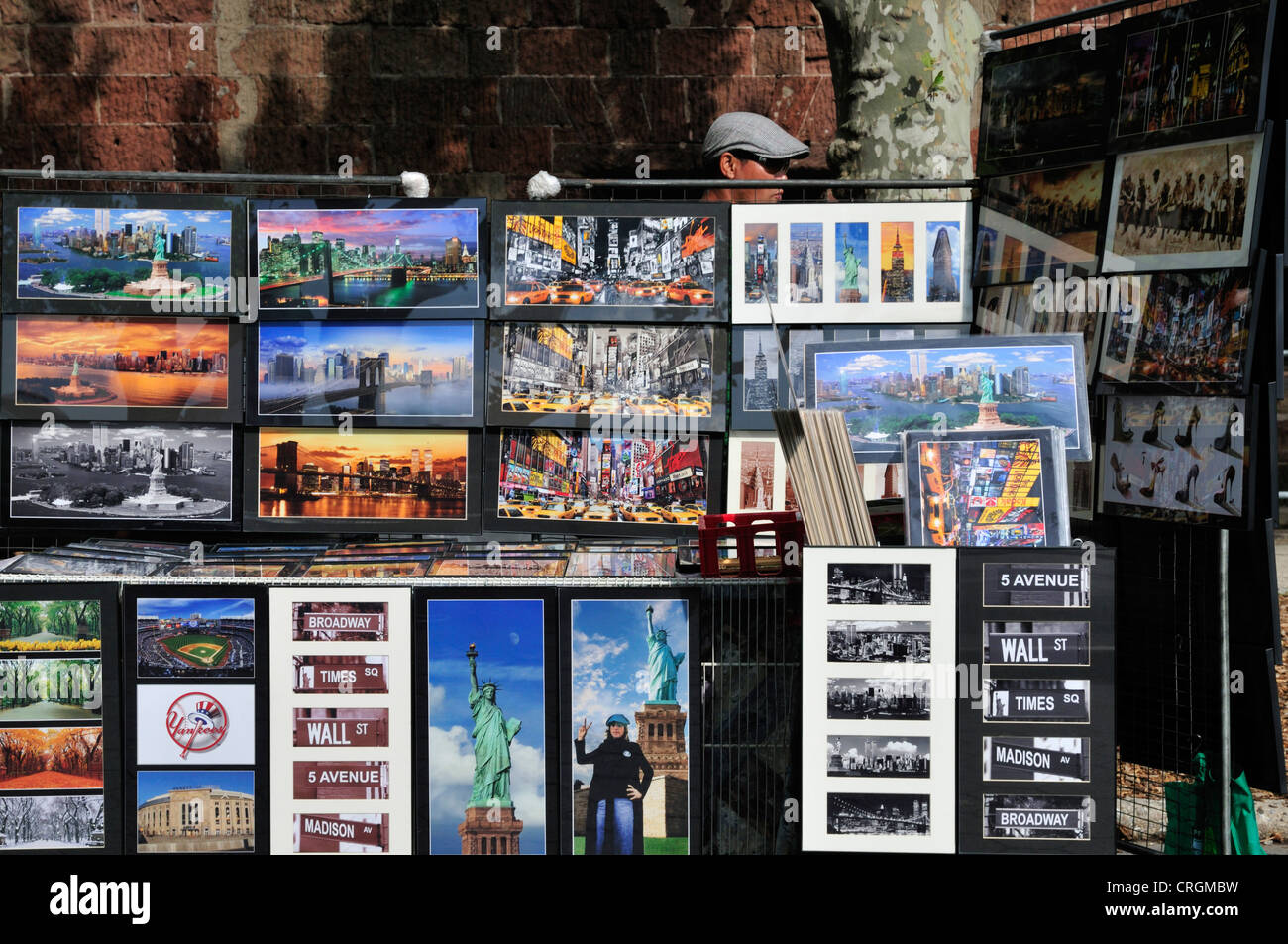 Ein Mann steht hinter einer großen Anzeige von Fotos, Schilder und andere Souvenirs aus New York am Battery Park Stockfoto