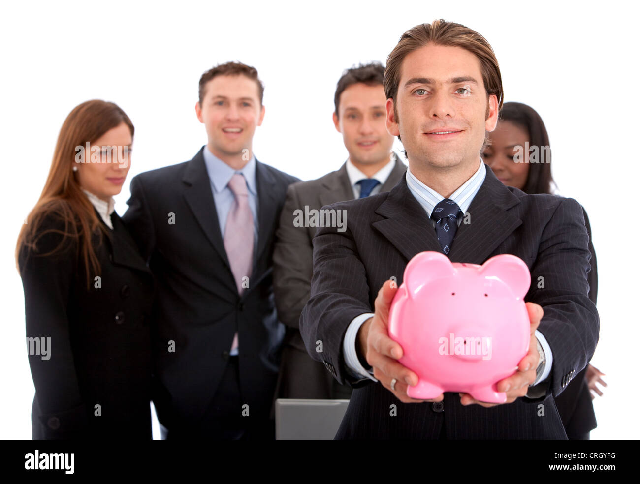 Business-Mann zeigt seine Ersparnisse in ein Sparschwein mit seinem Team hinter ihm Stockfoto