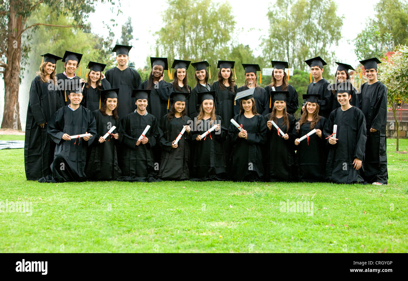 Gruppe von Absolventen mit Kleid, Quaste und Diplom, glücklich lächelnd Stockfoto